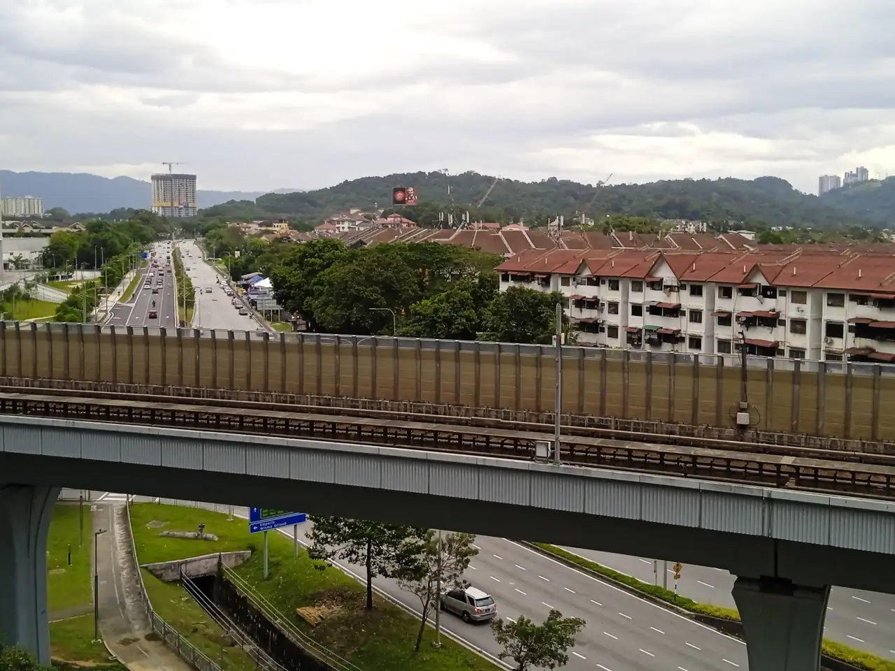 View from Emporis over the Kajang line viaduct and Persiaran Surian, with red-roofed houses and hills beyond
