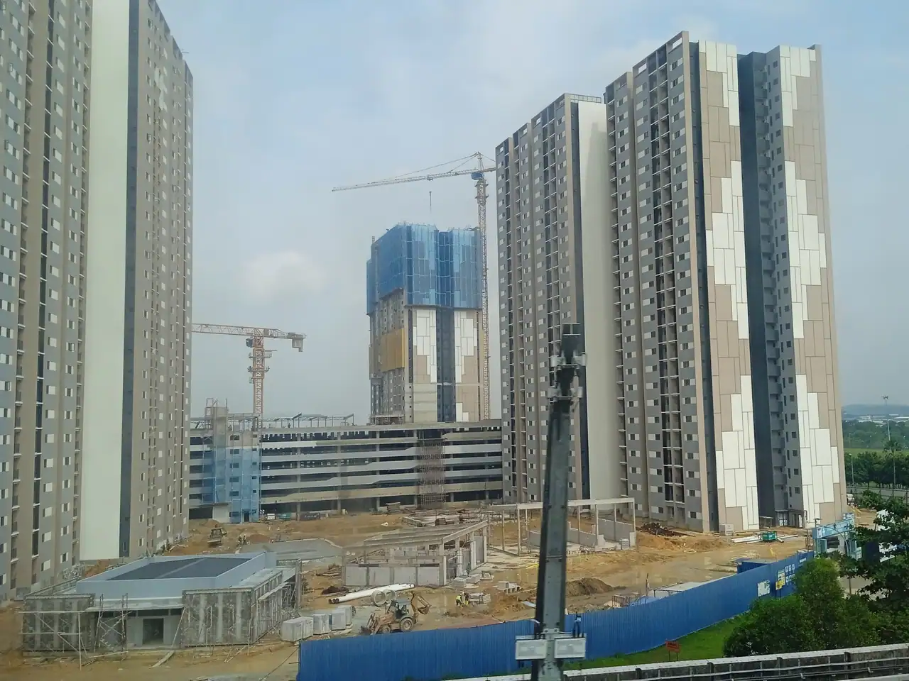 A wider view of the Idaman towers and the car park podium with cranes beyond