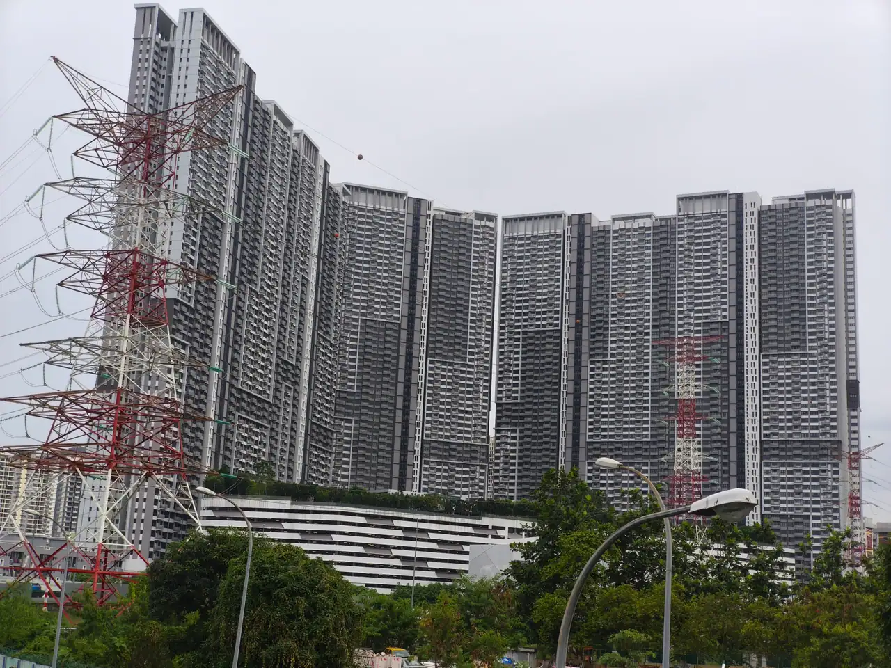 The curved row of M Vertica towers seen across open land with a pylon in the foreground