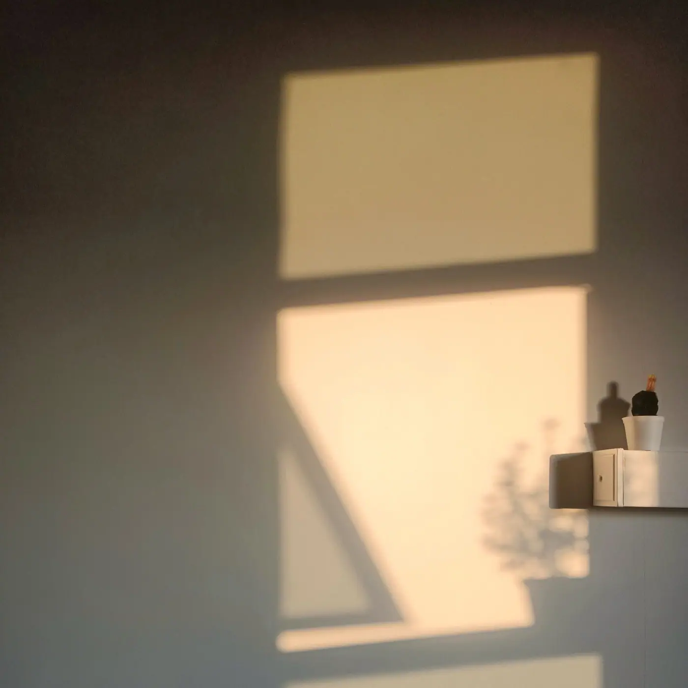 Bars of window light and shadow falling across a warm wall