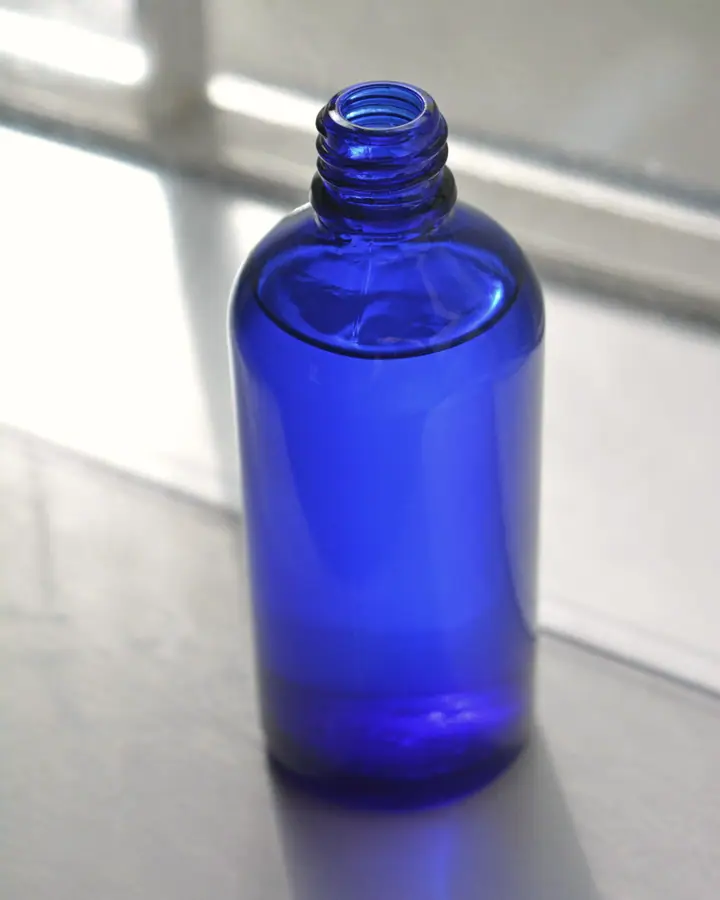 Cobalt blue glass bottle in soft window light on a pale sill